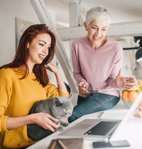 Two woman and a Cat Working on a Laptop